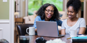 Two ladies looking at a laptop and laughing