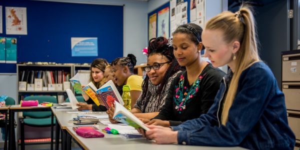 A row of ladies looking at textbooks.